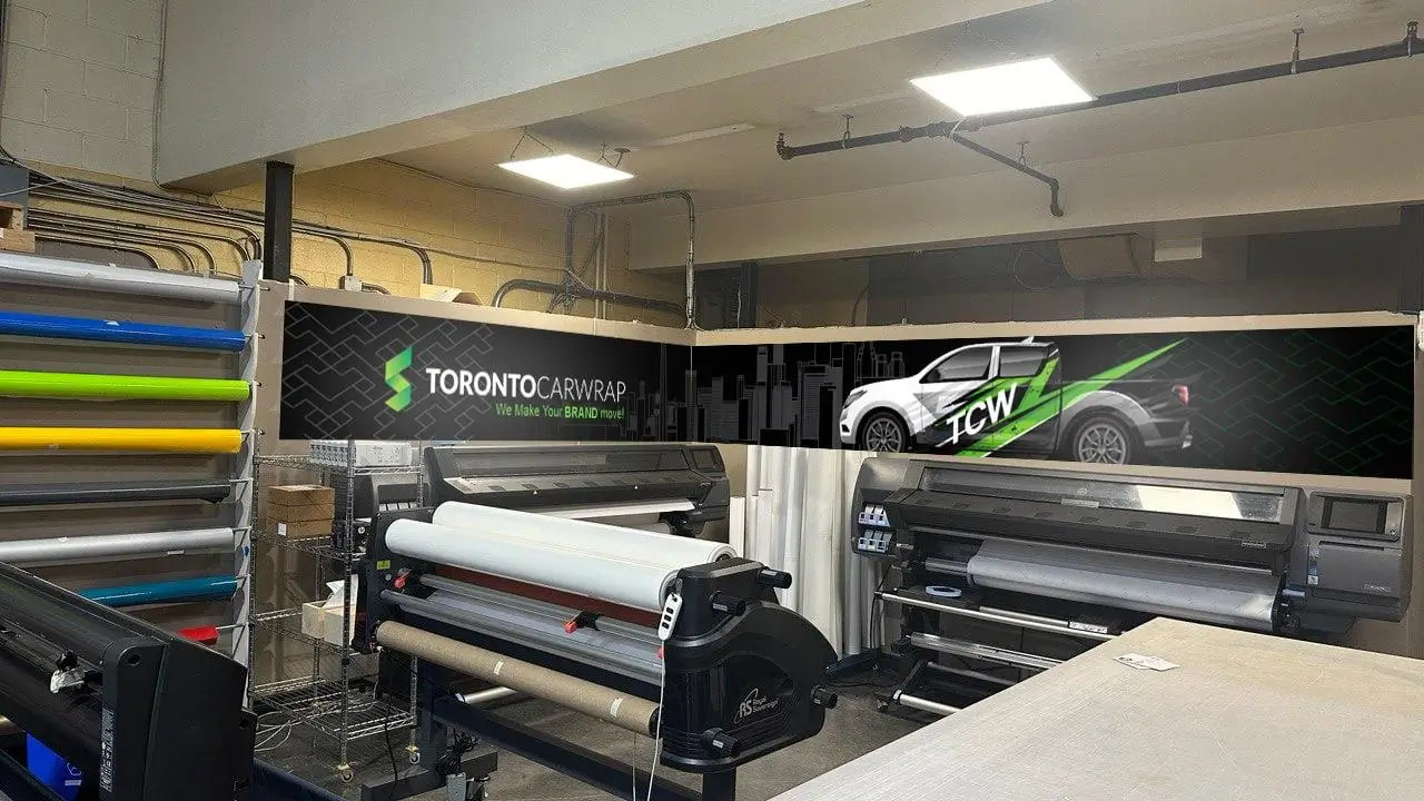 Toronto Car Wrap’s vinyl wrap printing facility featuring wide-format printers, custom wrap materials, and branded wall signage – professional vehicle wrap production shop in Toronto, Ontario